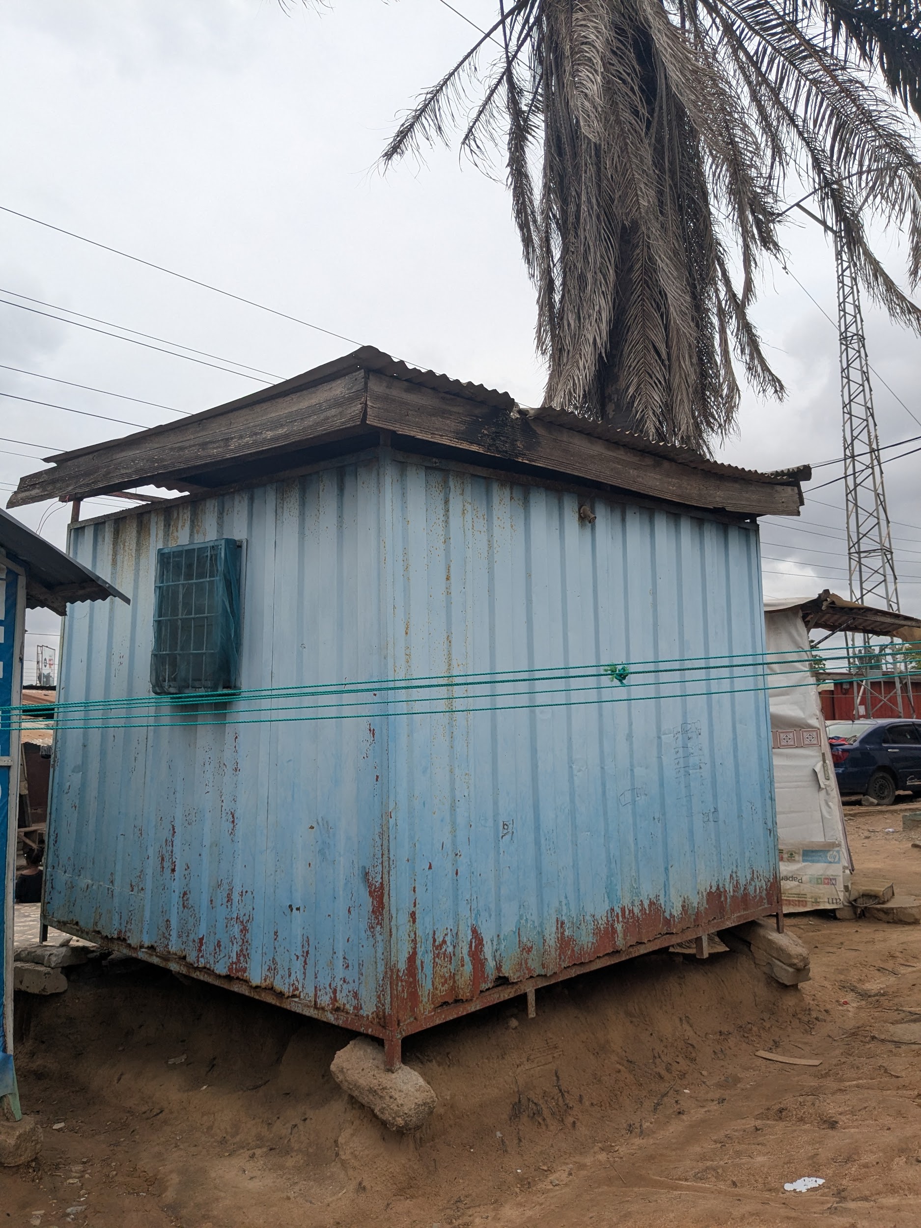 Blue corrugated zinc kiosk — a typical single-room dwelling in Agbogbloshie